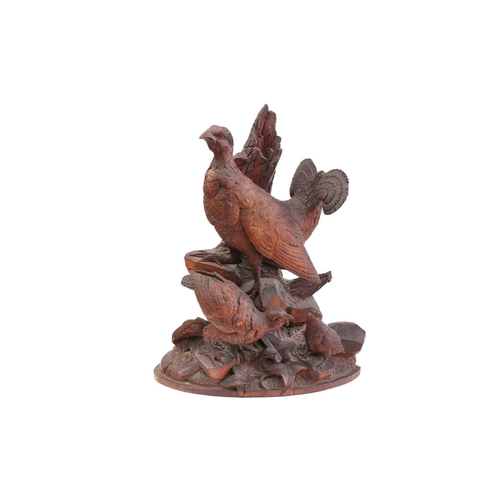 357 - A pair of Black Forest carved wood figures of partridges, with their offspring, on ivy-carved natura... 