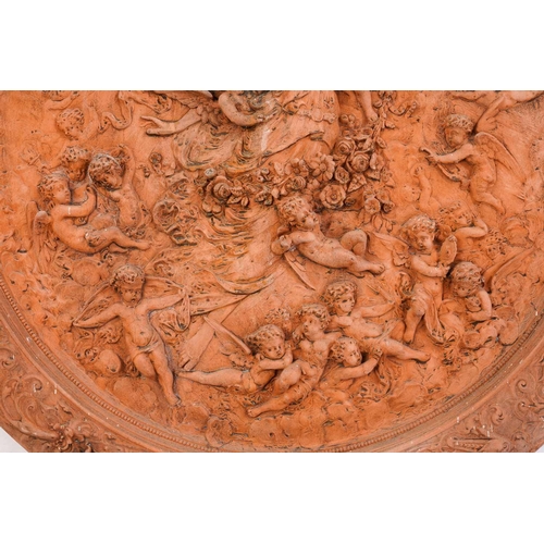 428 - A large terracotta relief garden plaque, depicting a Goddess surrounded by cherubs, within a floral ... 