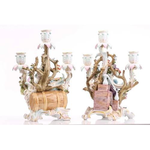 430 - A pair of Meissen three branch candelabra, depicting a figure seated with a spilling bag of gold and... 