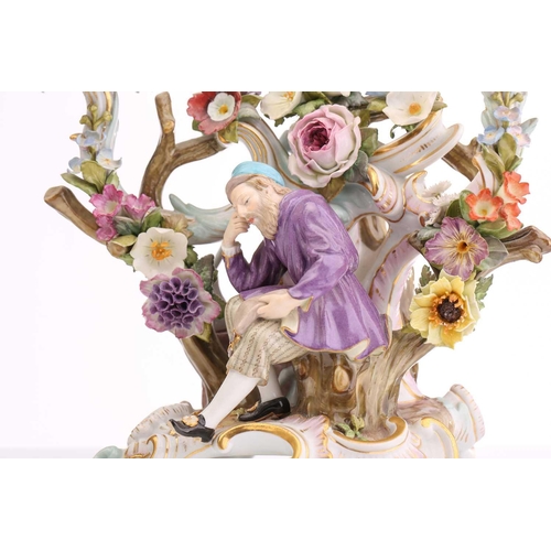 430 - A pair of Meissen three branch candelabra, depicting a figure seated with a spilling bag of gold and... 