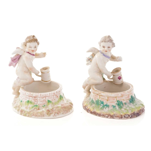 440 - A pair of Berlin salts, each with a putto standing over two bowls and scrolling feet painted with bi... 