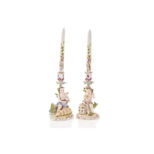 446 - A pair of Dresden porcelain candlesticks, with flower encrusted porcelain candles, each depicting pu... 