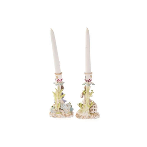 446 - A pair of Dresden porcelain candlesticks, with flower encrusted porcelain candles, each depicting pu... 