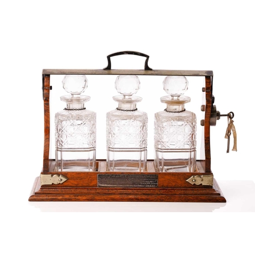 464 - An Edwardian oak and silver-plated three-bottle tantalus with silverplated fittings with a locking b... 