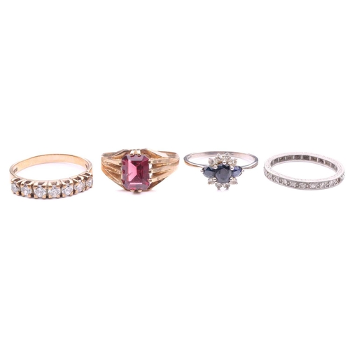 104 - A collection of four rings comprising a 9ct gold ring set with an emerald cut garnet, a diamond set ... 