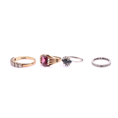 104 - A collection of four rings comprising a 9ct gold ring set with an emerald cut garnet, a diamond set ... 