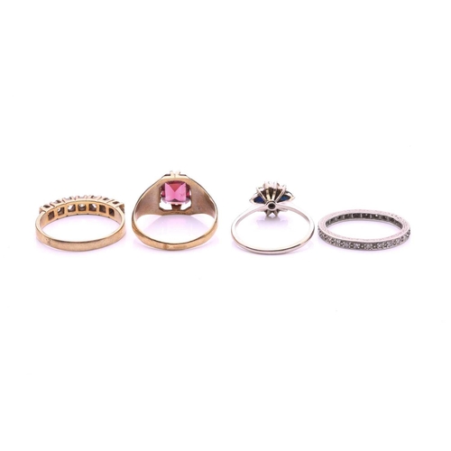 104 - A collection of four rings comprising a 9ct gold ring set with an emerald cut garnet, a diamond set ... 