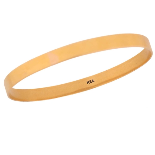 117 - A yellow metal closed bangle, with a solid flat band, marked as 'K22', internal circumference approx... 