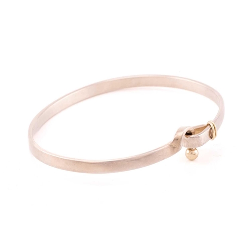 130 - Tiffany & Co. - A two-tone hook and eye bangle, comprising an oval-shaped flat bangle bracelet, sign... 