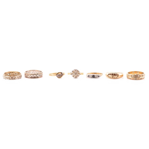 151 - A collection of seven rings, comprising of a three-stone ring set into yellow metals stamped 18ct, a... 