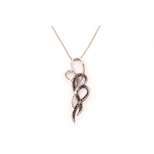 157 - A white and black diamond pendant on chain, of scrollwork design, white and black oxidised mount, wi... 