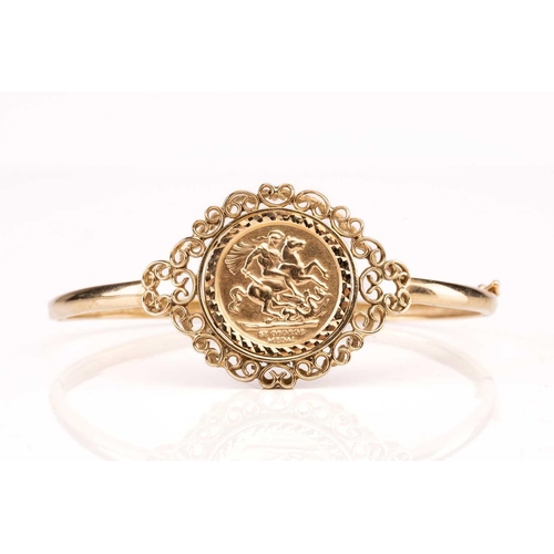 188 - A 9ct gold hinged bangle, set with embossed George medal replica, 10.9g