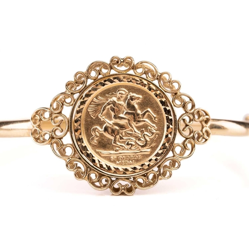 188 - A 9ct gold hinged bangle, set with embossed George medal replica, 10.9g