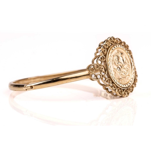 188 - A 9ct gold hinged bangle, set with embossed George medal replica, 10.9g