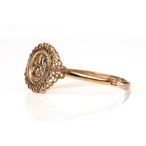 188 - A 9ct gold hinged bangle, set with embossed George medal replica, 10.9g