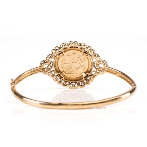 188 - A 9ct gold hinged bangle, set with embossed George medal replica, 10.9g