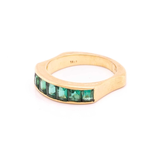 194 - An emerald half-eternity ring, channel-set with a row of seven step-cut emeralds, to an ergonomic ri... 