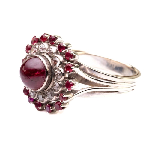 208 - A cabochon ruby and diamond cluster ring; the central, circular ruby in collet mount above a border ... 