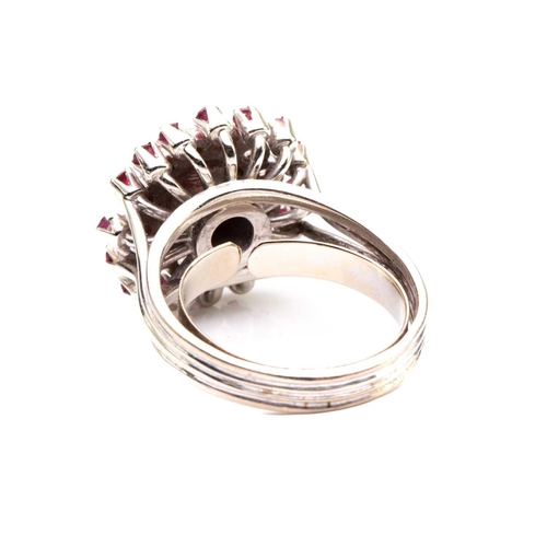 208 - A cabochon ruby and diamond cluster ring; the central, circular ruby in collet mount above a border ... 