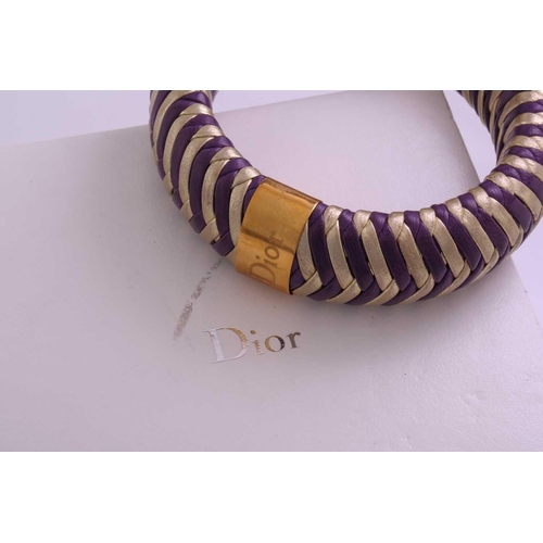 215 - Dior; a herringbone woven leather bangle in purple and gold with engraved gold-tone metal band engra... 