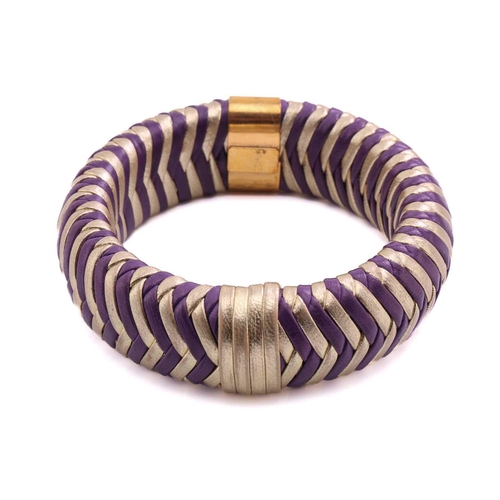 215 - Dior; a herringbone woven leather bangle in purple and gold with engraved gold-tone metal band engra... 