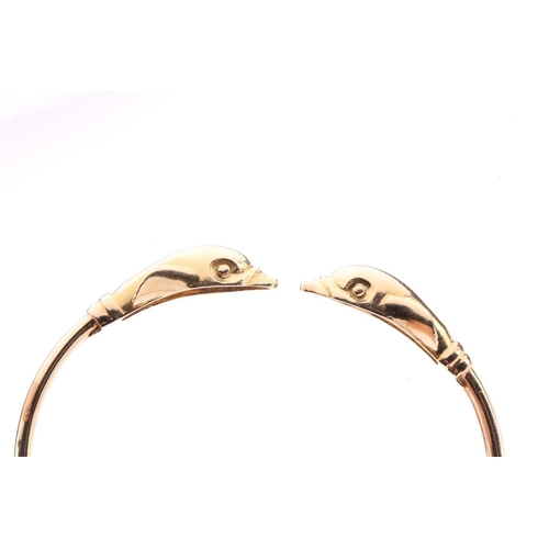 230 - A dolphin torque bangle, with a plain band terminating with dolphin heads, yellow metal marked '585'... 