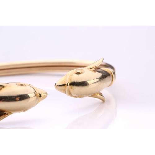 230 - A dolphin torque bangle, with a plain band terminating with dolphin heads, yellow metal marked '585'... 