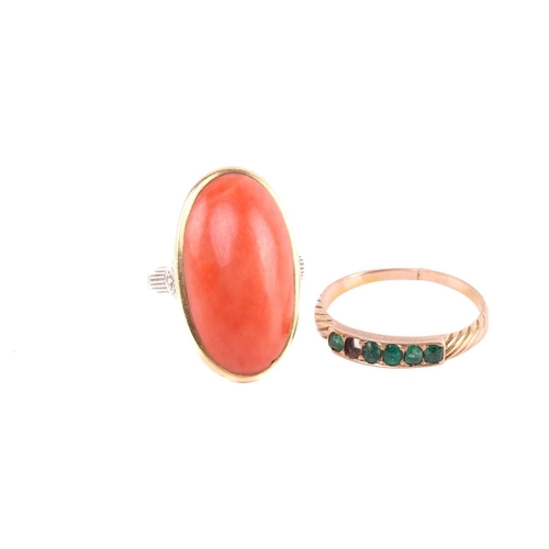 232 - A precious coral ring and an emerald half-hoop ring; the coral dress ring comprises a large oval-sha... 