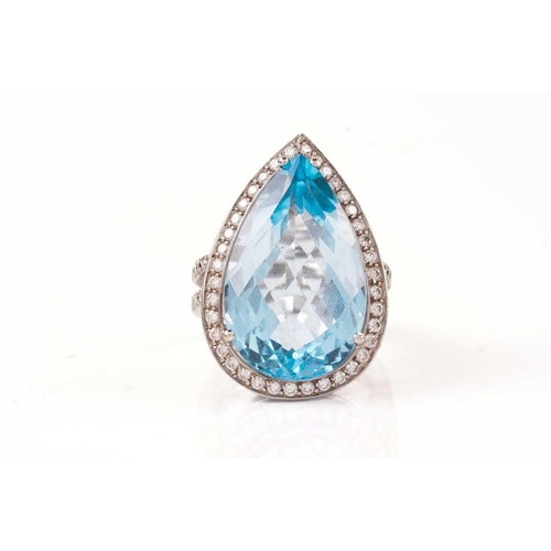 61 - A topaz and diamond halo ring, consisting of a large pear-shaped sky blue topaz, approximately measu... 