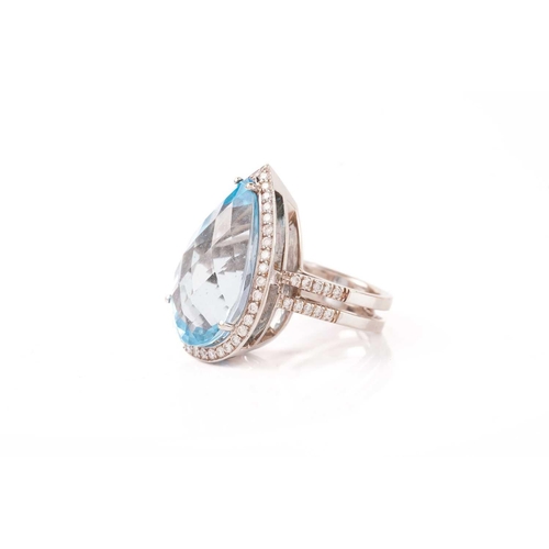 61 - A topaz and diamond halo ring, consisting of a large pear-shaped sky blue topaz, approximately measu... 