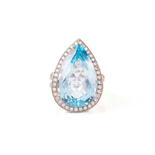 61 - A topaz and diamond halo ring, consisting of a large pear-shaped sky blue topaz, approximately measu... 