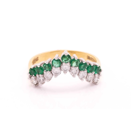 63 - An emerald and diamond ring in 18ct gold, of chevron design, comprising a row of nine brilliant-cut ... 