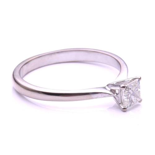 97 - A single stone diamond ring; the princess cut diamond in four claw mount to a plain 18-carat white g... 