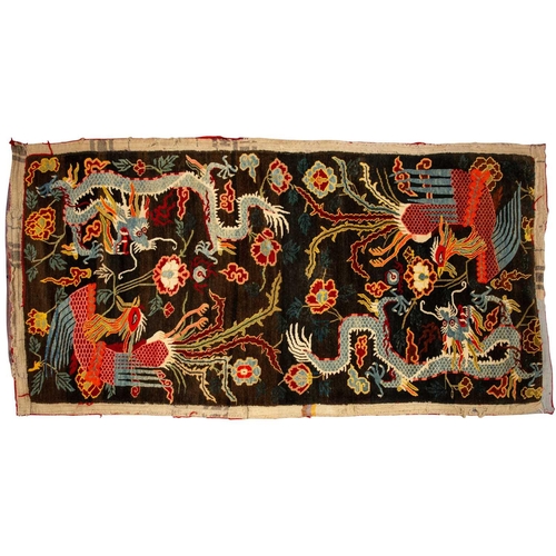 156 - A black ground Tibetan pictorial rug, late decorated with a battling dragon and phoenix an early 20t... 