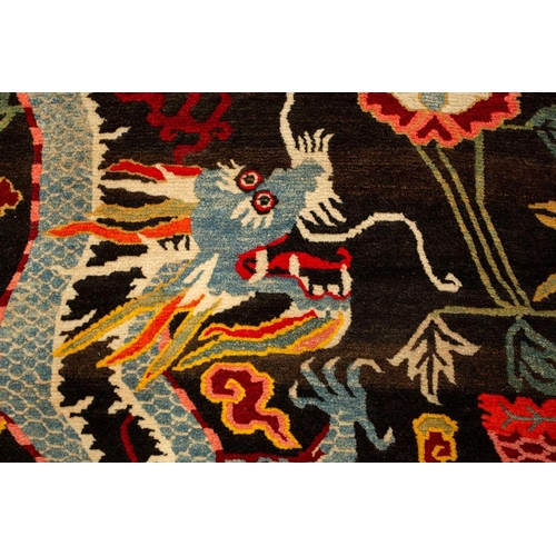 156 - A black ground Tibetan pictorial rug, late decorated with a battling dragon and phoenix an early 20t... 