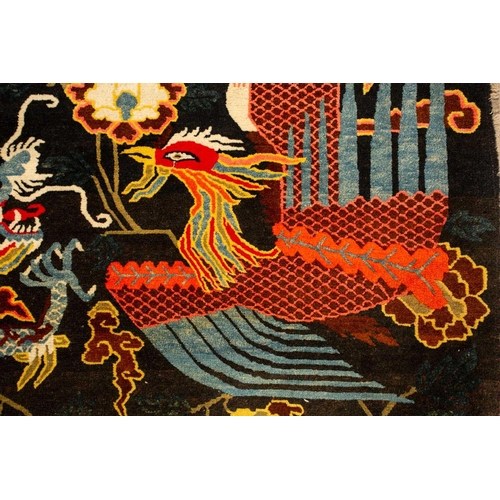 156 - A black ground Tibetan pictorial rug, late decorated with a battling dragon and phoenix an early 20t... 