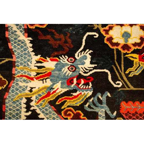 156 - A black ground Tibetan pictorial rug, late decorated with a battling dragon and phoenix an early 20t... 