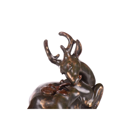 127 - A Chinese porcelain simulated bronze figure of a recumbent stag with a sprig of lingzhi, the green g... 