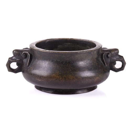 128 - A Chinese bronze censer, with thick walled compressed body, with applied elephant mask handles, apoc... 