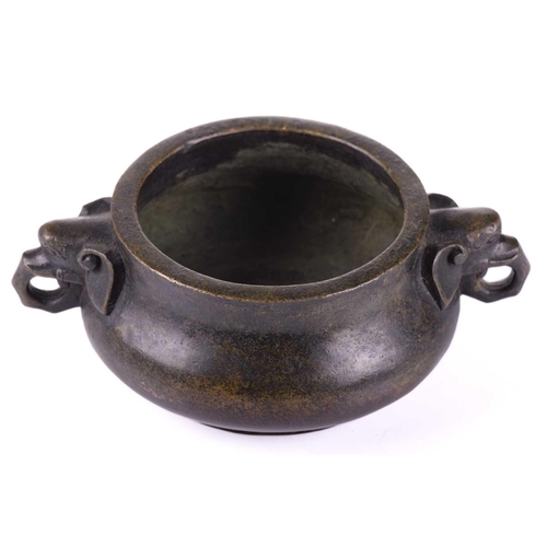 128 - A Chinese bronze censer, with thick walled compressed body, with applied elephant mask handles, apoc... 