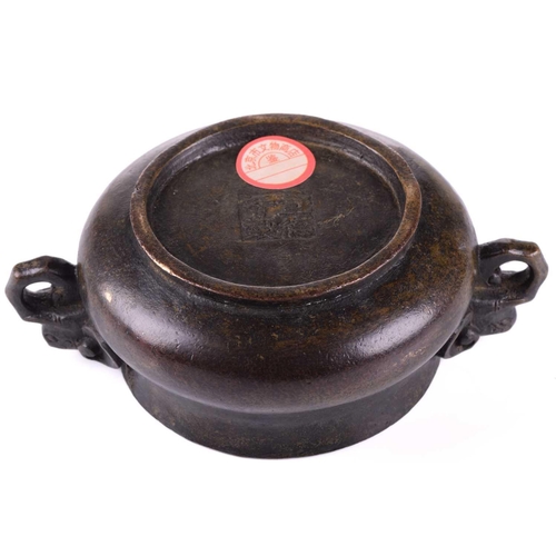 128 - A Chinese bronze censer, with thick walled compressed body, with applied elephant mask handles, apoc... 