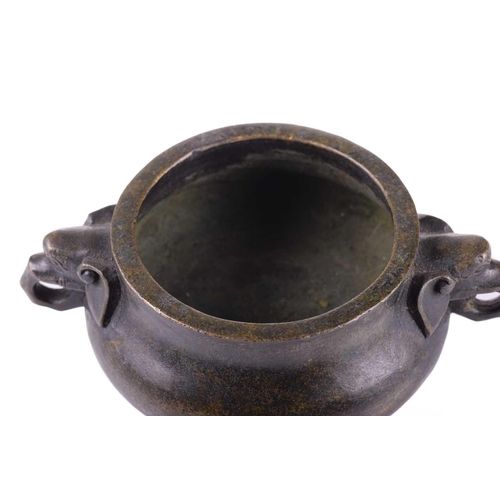 128 - A Chinese bronze censer, with thick walled compressed body, with applied elephant mask handles, apoc... 