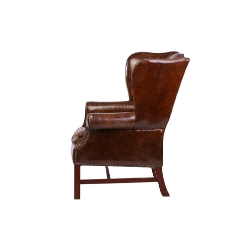 195 - A George III-style distressed hide upholstered gentleman's wingback armchair, 20th century, with mel... 