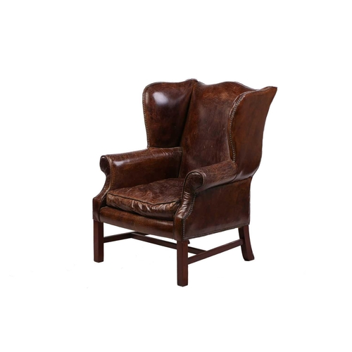 195 - A George III-style distressed hide upholstered gentleman's wingback armchair, 20th century, with mel... 