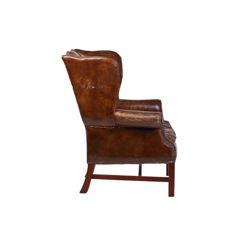 195 - A George III-style distressed hide upholstered gentleman's wingback armchair, 20th century, with mel... 