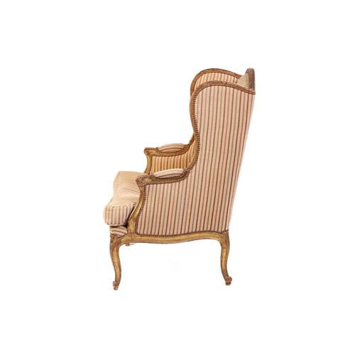 237 - A Louis XV style bergere wing chair, 19th century, with carved wood and gilt gesso frame and striped... 