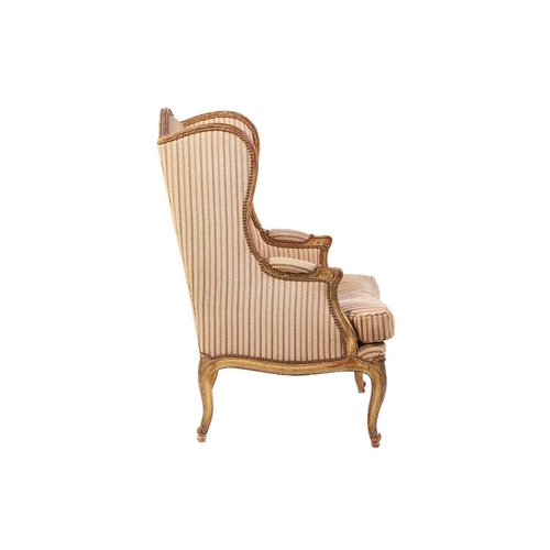 237 - A Louis XV style bergere wing chair, 19th century, with carved wood and gilt gesso frame and striped... 