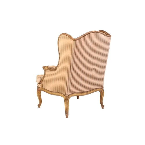 237 - A Louis XV style bergere wing chair, 19th century, with carved wood and gilt gesso frame and striped... 