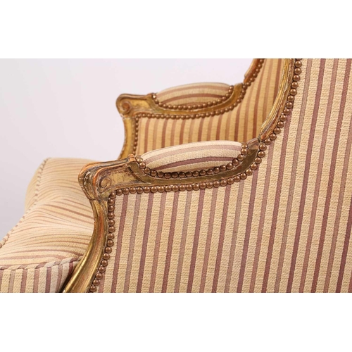 237 - A Louis XV style bergere wing chair, 19th century, with carved wood and gilt gesso frame and striped... 