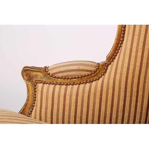 237 - A Louis XV style bergere wing chair, 19th century, with carved wood and gilt gesso frame and striped... 